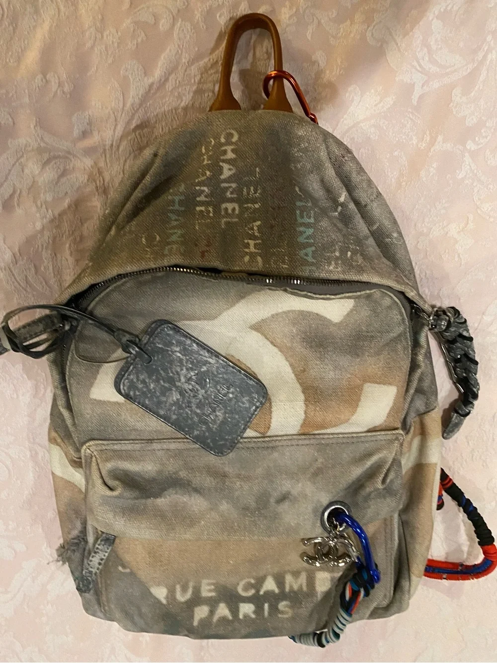 CHANEL Faded Beige Canvas Backpack with Multicolor Strap and Silver-Tone Charm
